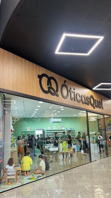 Fachada da Óticas Quel dentro do supermercado Covabra, com vitrine de vidro e letreiro em madeira